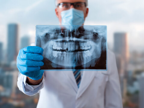 Medical professional wearing protective gear examining a dental x-ray film with urban cityscape in soft focus background for healthcare concept