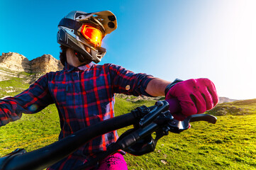 man on a mountain bike trains in the beautiful mountains. A wide-angle front view of the handlebars and the rider's hands, wearing a protective helmet