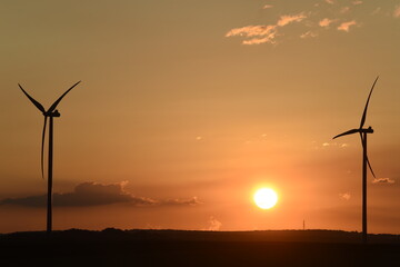 lever de soleil sur des &eacute;oliennes &agrave; contre-jour; ciel d&eacute;grad&eacute; couleur bleue et orange avec des petits nuages cumulus blancs gris et noirs