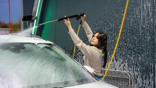 Woman using a pressure washer at a car wash