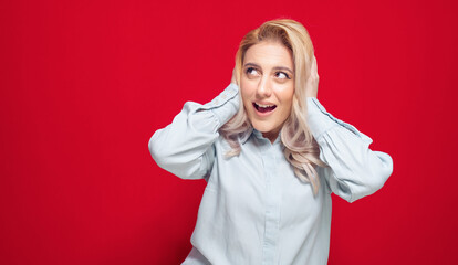 Astonished woman with hands on his head, isolated on red background. Shocked girl