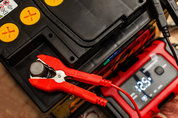 car battery with charger and red clamp on terminal