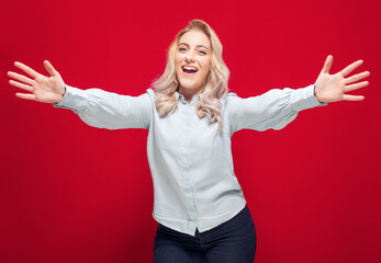 Lovely woman with raised arms up going to you, isolated on red background. Welcome concept