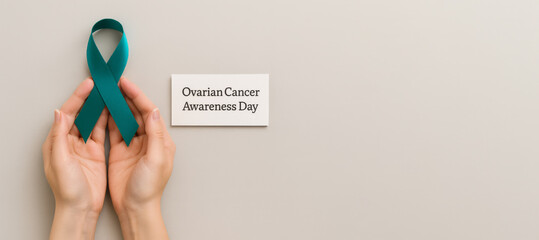 Teal ribbon held in hands for ovarian cancer awareness day, concept with text space