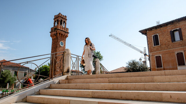 Woman walking near historical tower in Murano, Italy