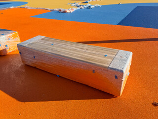 new wooden benches wrapped in protective film placed on a freshly installed colorful playground or stadium surface