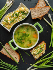 Fresh healthy natural chicken broth with veggies and egg salad sandwiches for cold days to keep warm and get nutrition and vitamins. Bowl portion with hot homemade broth with baked whole wheat bread