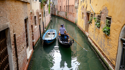 Gondolier navigating a narrow Venetian canal