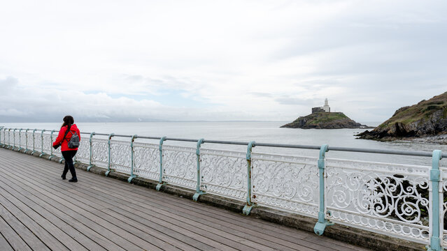 Woman walking on Mumbles Pier with lighthouse view