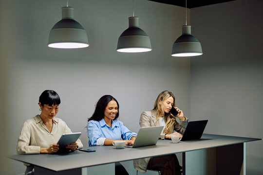 Multiracial businesswomen working with laptops and a tablet, making a call and having a meeting in a modern office
