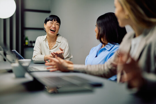 Diverse businesswomen enjoying a productive meeting, collaborating and finding joy while working in a modern office environment