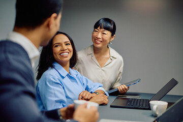 Diverse business women smiling, actively participating in a team meeting, fostering collaboration and positive atmosphere