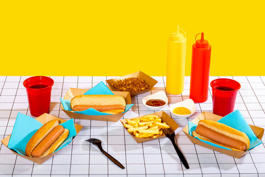 Hot dogs and fries with condiment bottles on a table