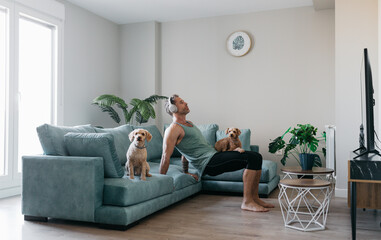 Man training at home with dogs on a sofa