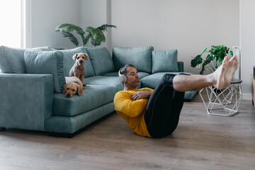Man exercising at home with headphones and dogs nearby