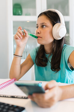 Girl studying with headphones on at home desk