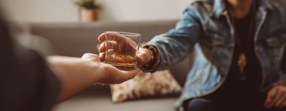 The glass of whiskey being handed across a cozy living room sofa - Powered by Adobe