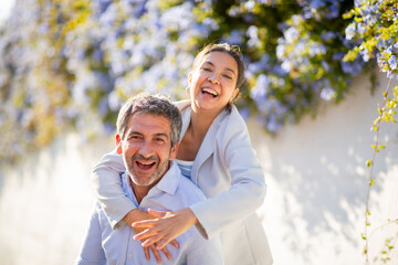 Obraz premium Cheerful couple laughing during playful moment under blue flowers
