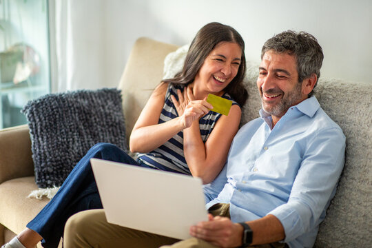 Happy couple shopping online together on a laptop at home