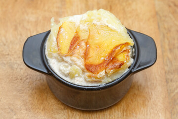 Gratin dauphinois dans un petit pot noir sur une table en bois