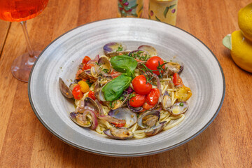 Linguine alle vongole (Linguines aux palourdes) – plat italien classique servie avec tomates, oignons confits et basilic