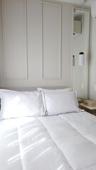 Elegant Bedroom with Cozy Bed, Light Decor, and Warm Sunlight. Vertical photo