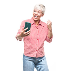 Excited adult woman on mobile phone holds fist, isolated on white background.