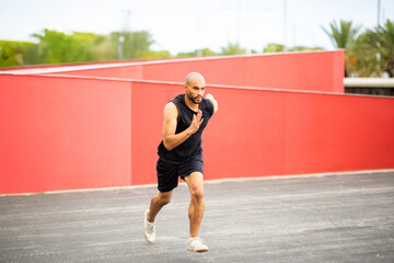 Obraz premium Man in black sportswear sprinting outdoors with focus and power