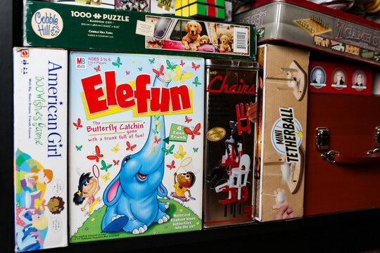 A shelf of board games and puzzles, including the Elefun butterfly catching game, an American Girl game, a Cobble Hill puzzle, and a mini tetherball set. For Editorial Use Only.