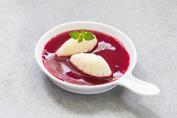 Sweet Cottage cheese quenelles with cherry sauce. With mint. On a plate