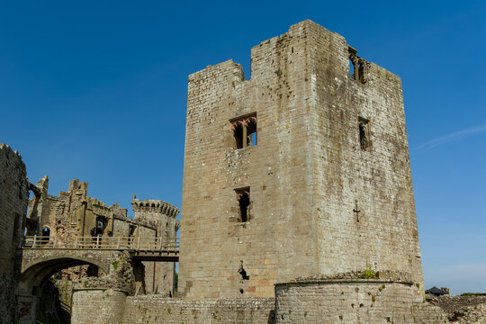 Ancient stone ruins of a 15th-century Welsh castle against a clear blue summer sky