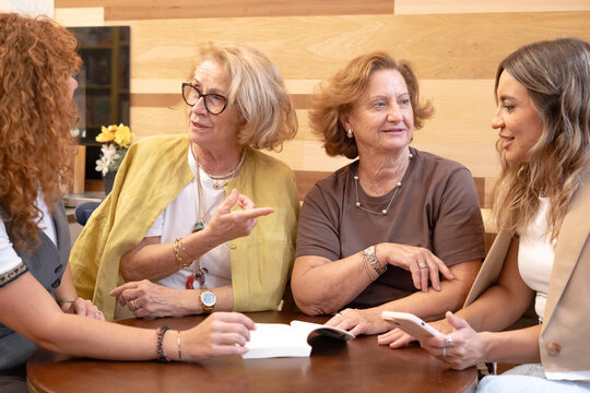 Women friends discussing ideas at book club meeting - Powered by Adobe