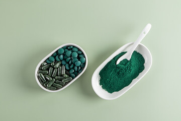 Top view of spirulina tablets and powder on green background