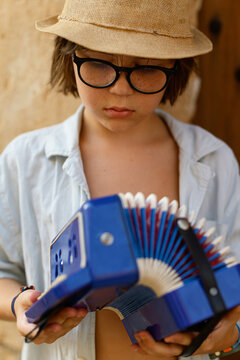Child playing with a blue toy accordion and hat