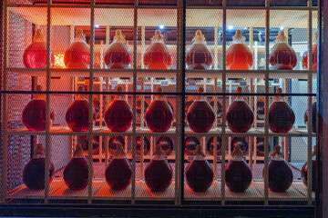 Symmetrical display of glowing wine bottles behind mesh