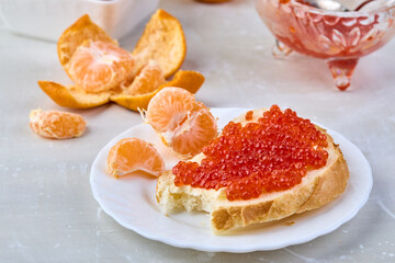 Sandwich with red caviar and tangerines. Traditional Russian treat on the New Year's table.