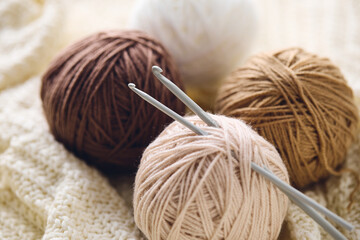 Crochet hooks and balls of beige and brown yarn on white knitted background. Knitting, crocheting supplies.