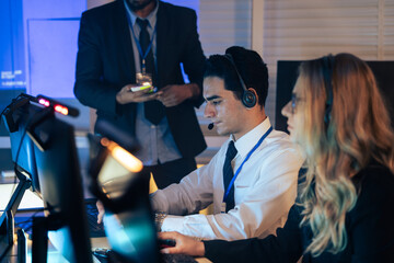 Customer service representative wearing a headset typing on a computer keyboard in modern call center office. Tech support or customer care in an efficient for business, IT, and communication
