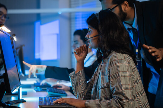 customer service agent team with headset typing on a computer keyboard. Modern call center office, providing efficient tech support, telemarketing and online communication during a late-night shift