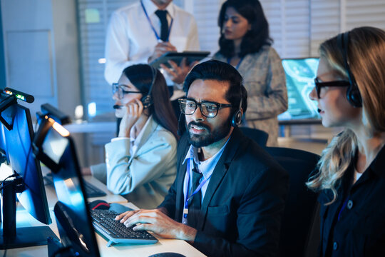 Customer service agent wearing a headset actively working diverse team call center. Technical support, telemarketing, work collaboration. consulting service. Group working overtime.