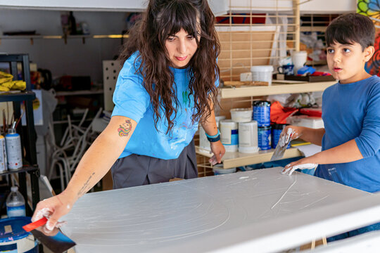 Visual artist teaching young boy to prepare a canvas for painting