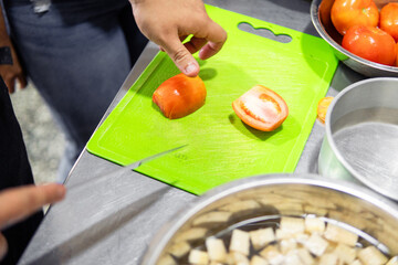 Hands preparing tomato during cooking class in kitchen