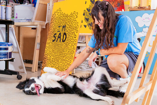 Visual artist relaxing with dog in her colorful studio