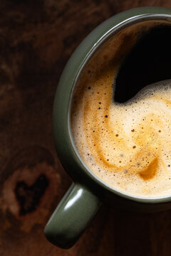 Close-up view of a steaming coffee cup with foam