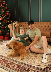 fam&iacute;lia celebra o natal com cachorro golden retriever em sala de natal 