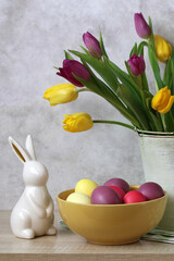 Easter bunny figurine with colored eggs and tulips