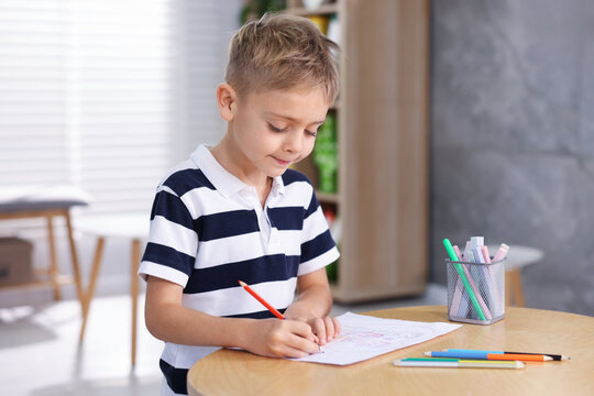Cute little boy drawing at wooden table indoors - Powered by Adobe