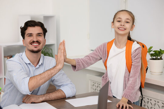 Teacher giving high five to girl in classroom