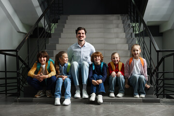 Fototapeta premium Happy teacher and children posing in school hallway