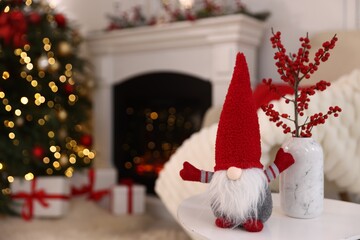 Naklejka premium Funny Christmas gnome on white table in decorated room. Space for text
